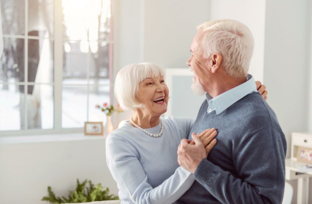 A senior couple holding each other with smiles on their faces as they just moved into their new retirement community suite