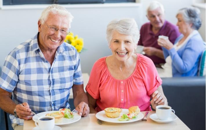 Two happy seniors dining in a senior living community without the worry of cooking for themsleves