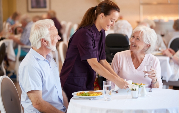 A senior couple having dinner in the dining hall of their retirement community