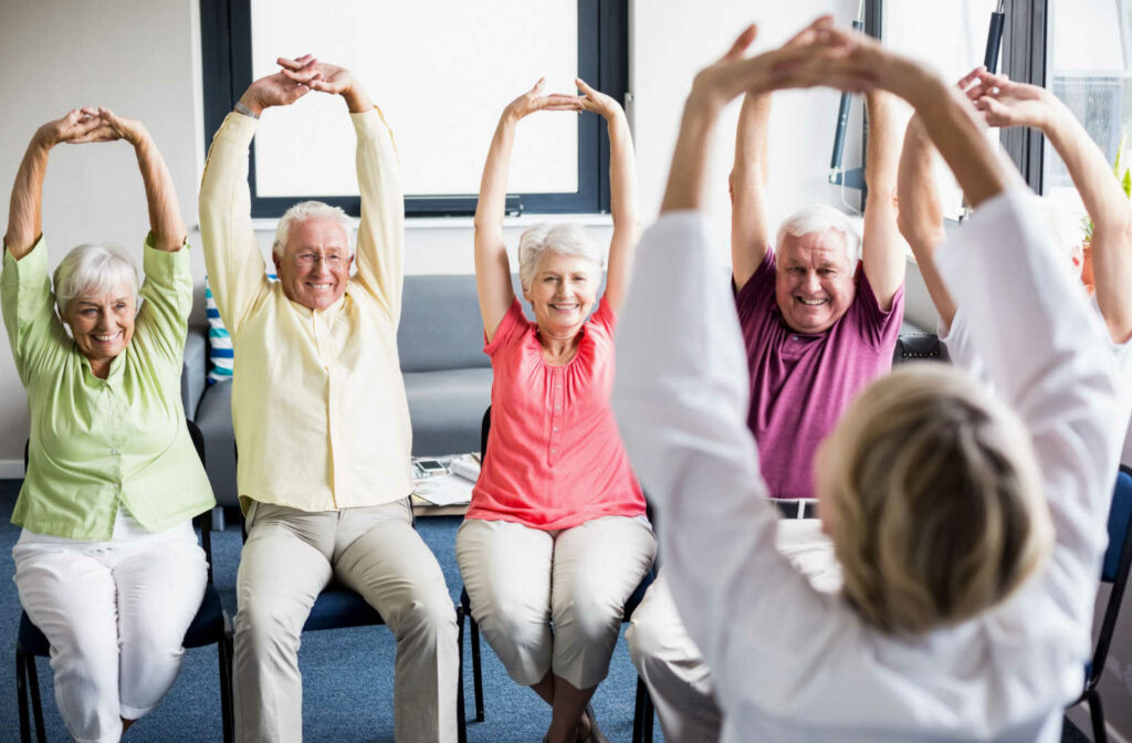 A group of senior living residents stretching during an exercise class.