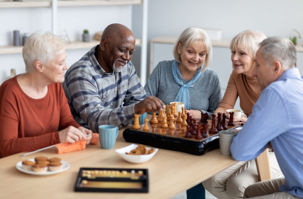 A group of seniors sitting at a table playing a game of chess in a senior living community