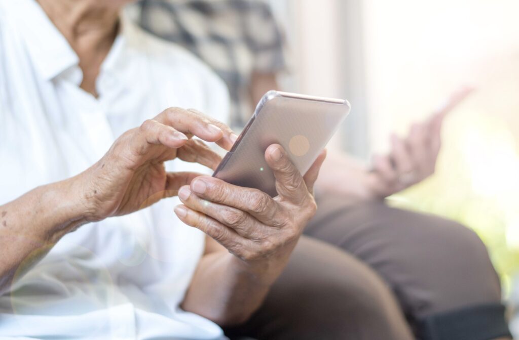 An older adult holding her phone to connect with loved ones via social media.