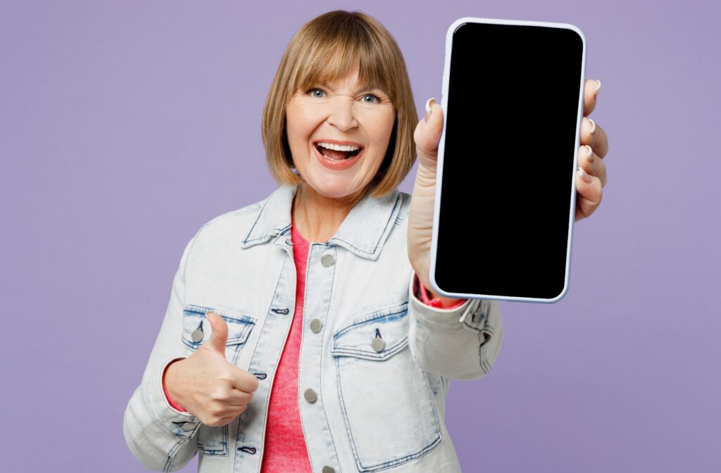 An older adult happily holding and sharing their smartphone screen.