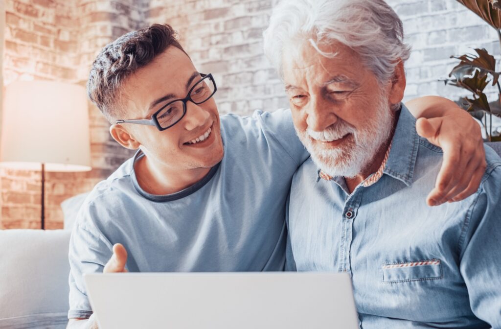 Grandson and grandfather discussing senior housing options together on a laptop