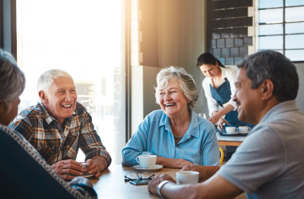 Group of older adults sitting together at a cafe, smiling and enjoying a conversation over coffee.