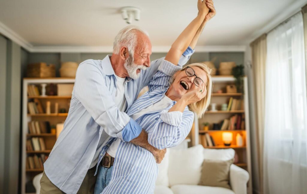 A senior couple dances in their living room.